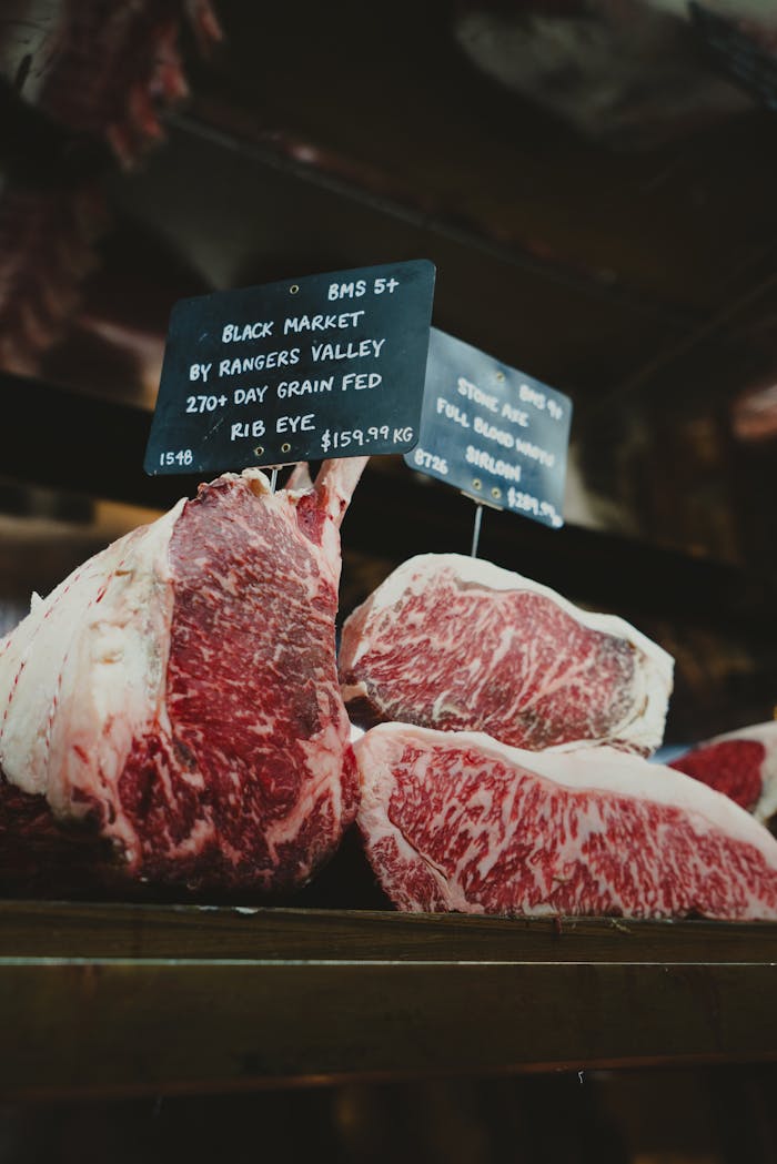 Close-up of premium rib eye steaks displayed at a retail market with signage.
