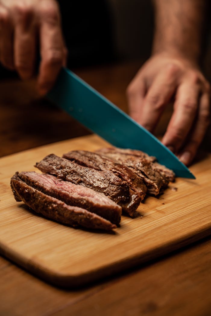 services-01 A chef skillfully slices perfectly cooked steak on a wooden board, showcasing culinary precision.